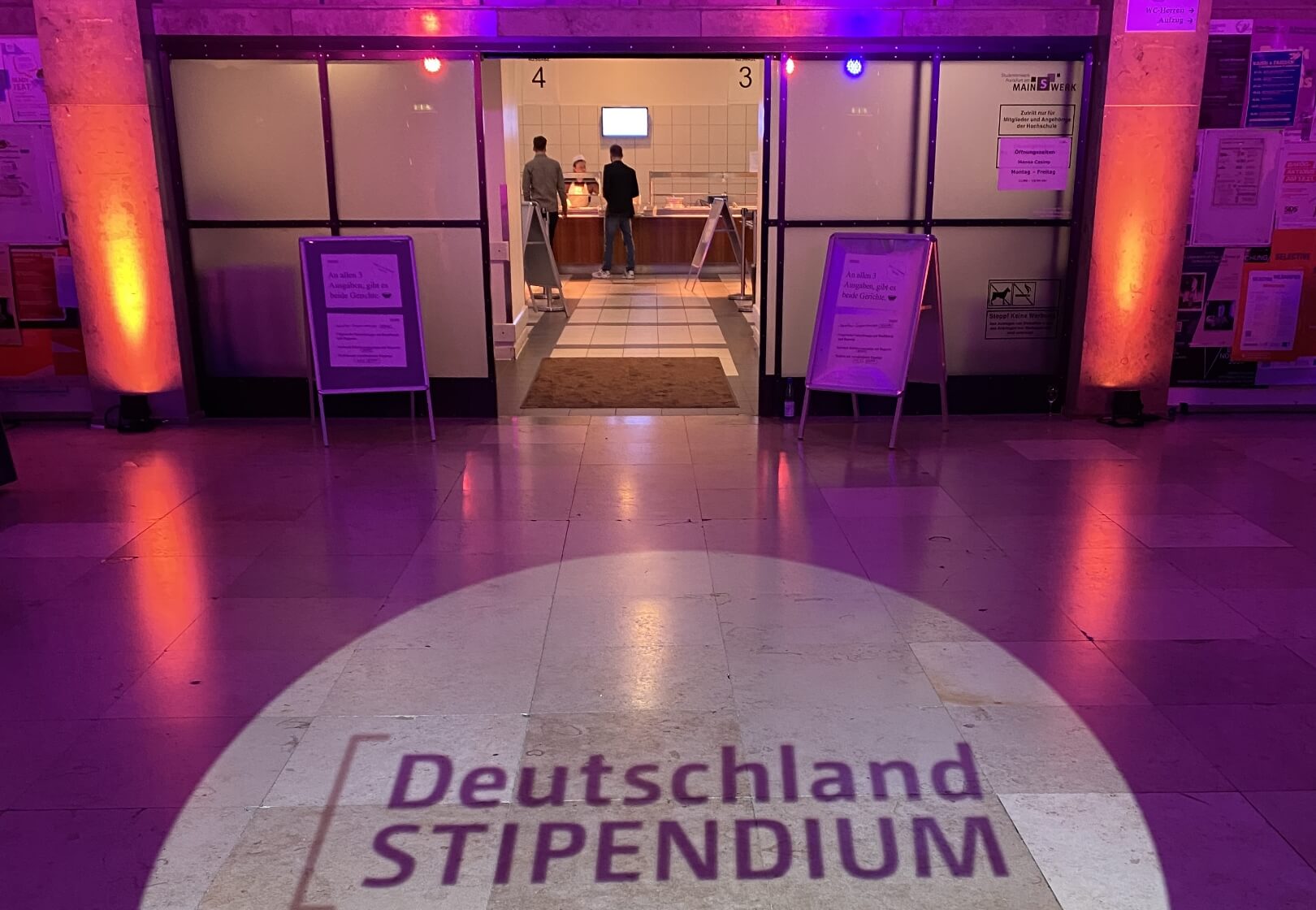 Ein festlich beleuchteter Zugang zur Veranstaltung. Auf dem Boden ist Deutschland STIPENDIUM projeziert.